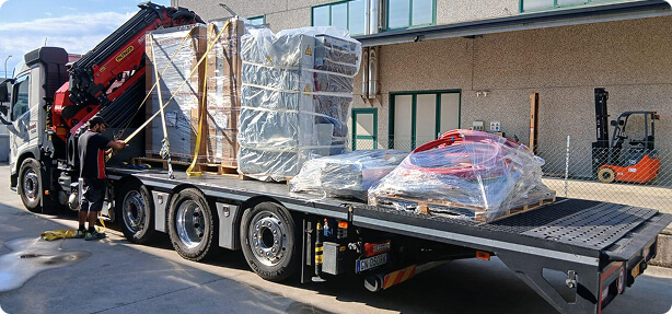 Camion con gru carico dei componenti di una cabina elettrica, pronti per il trasporto in cantiere